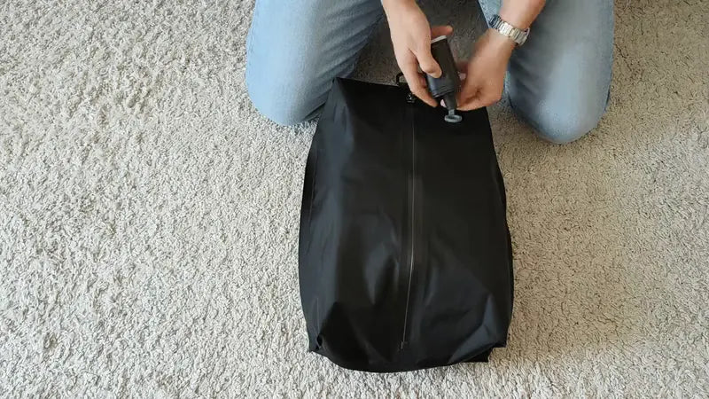 Pompe compacte posée sur la valve du sac de compression noir